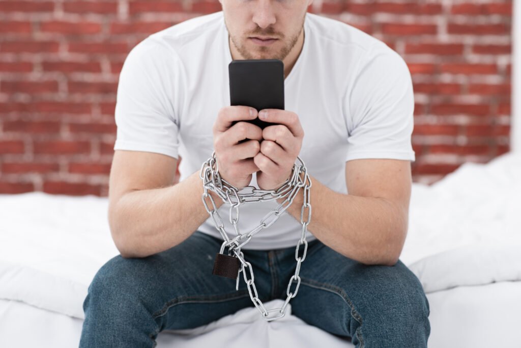 man-holding-his-phone-while-he-is-tied-up-with-chains-1-scaled.jpg.porn addiction symptoms